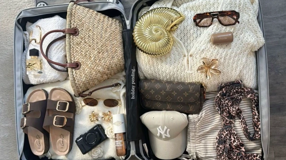 Flat lay of organized suitcase with stylish clothing, skincare, tech gadgets, and travel accessories tailored for women perfect visual for travel essentials for women.