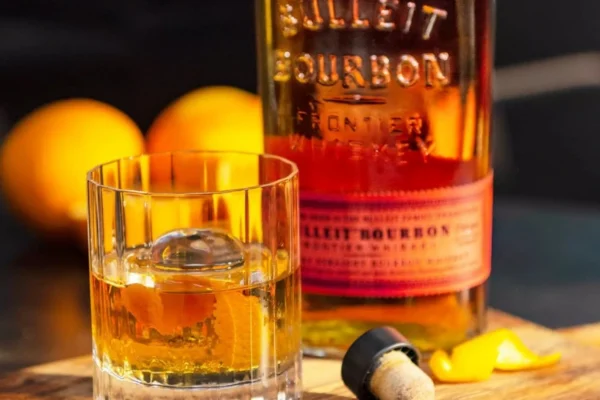 "Bulleit Old Fashioned cocktail served in a lowball glass with an orange twist and ice cubes"