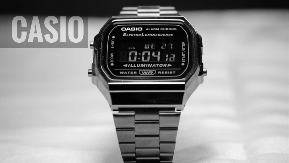 A close-up of a sleek Casîo digital wristwatch resting on a marble surface, showcasing its minimalist design and digital display. 