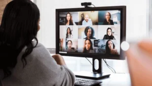 A diverse group of hiring remote employees working on laptops from home, connected via video call.

