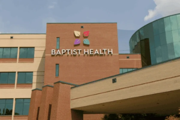 Front exterior of Baptist Health Paducah KY hospital campus, showcasing the modern brick and glass façade under a partly cloudy sky.