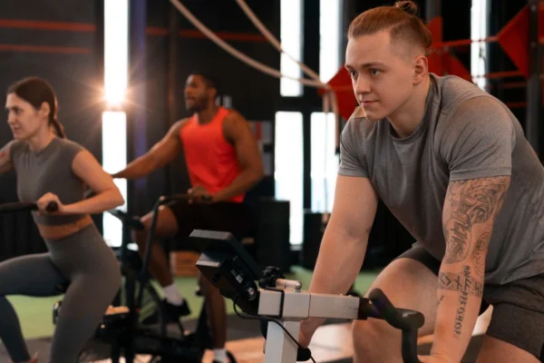 Kelsey Kane gym trainer leading energetic group fitness class at Fitness Junction with members using GHD machines and TT bikes for strength training