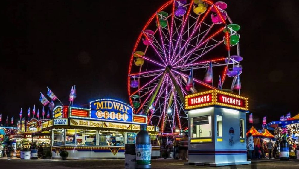 Crowd enjoying the Minnesota State Fair with food stands, rides, and live entertainment under sunny skies