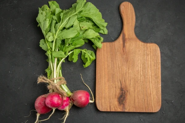 Fresh pravi celer stalks and roots displayed on wooden cutting board with traditional Balkan kitchen ingredients
