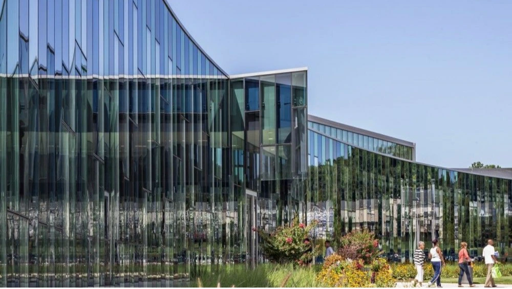 Exterior façade of the Southern Regional Technology and Recreation Complex, showcasing its colorful sweeping glass curtain wall under a clear sky.